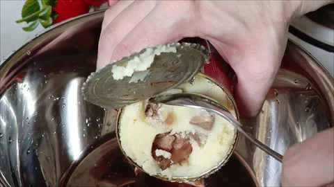 Womens hands spoon beef meat from a tin can into a metal cup Video stock 313103067