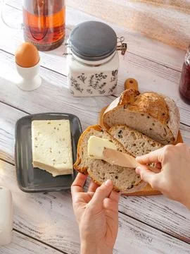 Women's hands spread butter on bread Stock Photos