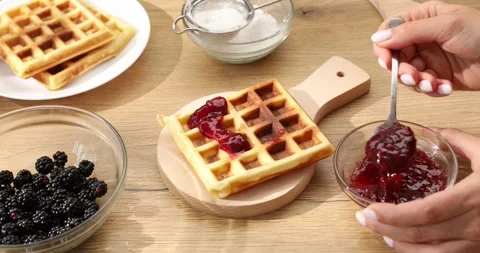 Women's hands spread raspberry jam on Belgian waffles. Stock Footage 248766655