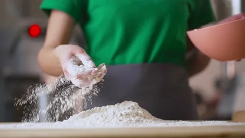 Women's hands sprinkle flour on the dough on the table, slow motion, sunlight Stock Footage 189241698