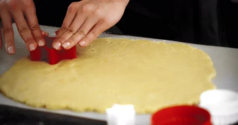 Women's hands squeeze out a star mold on a rolled-out sand dough Stock Footage 182834077