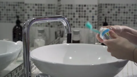 Women's hands squeeze toothpaste from a tube onto a toothbrush in the bathroom Stock Footage 268843537