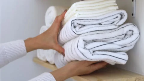Women's hands stack a stack of clean towels on a shelf. Stock Footage 236964534
