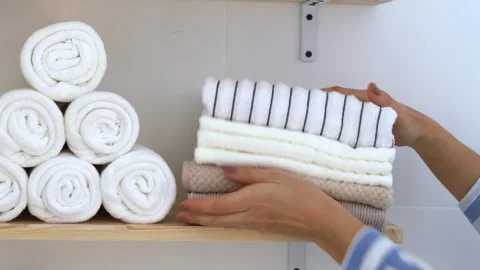 Women's hands stack a stack of clean towels on a shelf. Stock Footage 251518347