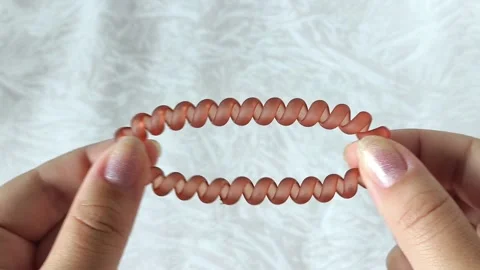 Womens hands stretch a spring-loaded hair band. Hair accessories. Stock Footage 313979107