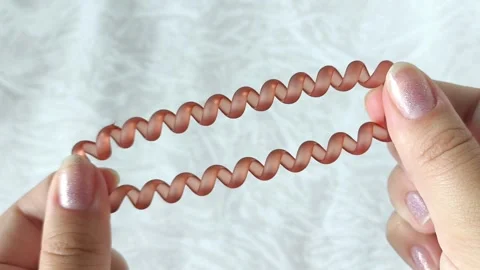 Womens hands stretch a spring-loaded hair band. Hair accessories. Stock Footage 313979427