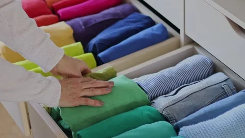 Women's hands take bright rainbow clothes from a wardrobe drawer. The concept of Stock Footage 245870269