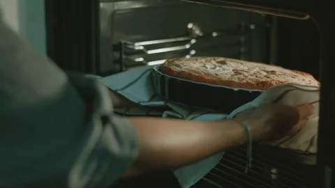 Women's hands take the cake out of the oven. Cooking. Stock Footage 130008964