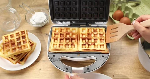 Women's hands take out cooked waffles from electric waffle iron. Stock Footage 248766243