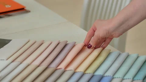 Women's hands touch samples of pastel-colored fabrics for upholstered children's Stock Footage 255232525