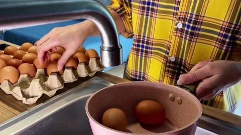 Women's hands transfer chicken eggs from a tray to a saucepan before boiling. Stock Footage 338076744