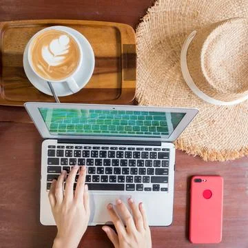 Women's hands typing on computer with coffee and smart phone Stock Photos
