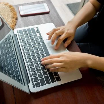Women's hands typing on computer with coffee and smart phone Stock Photos