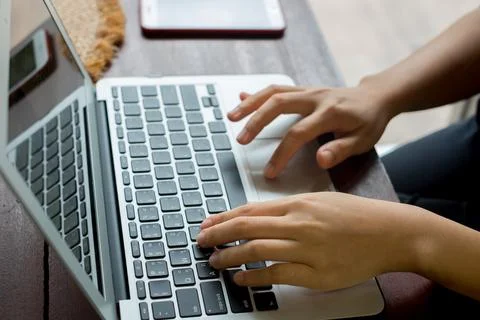 Women's hands typing on computer with coffee and smart phone Stock Photos
