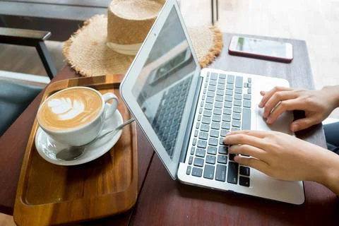 Women's hands typing on computer with coffee and smart phone Stock Photos