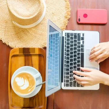 Women's hands typing on computer with coffee and smart phone Stock Photos