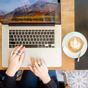 Women's hands typing on computer with coffee Stock Photos