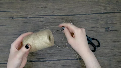 Women's hands unwind a string from a spool and cut a piece with scissors. D.. Stock Footage 319747435