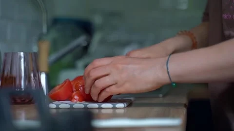 Women's Hands use a knife to cut a red juicy tomato on a cutting board. Cut a Stock Footage 306306762