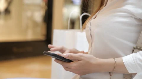 Women's hands use a smartphone on the background of the package with shopping at Stock Footage 111319417