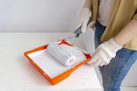 Womens hands using paint roller while working indoors Stock Photos