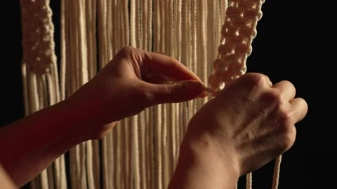 Women's hands weave a macrame pattern in creative workshop on black background Stock Footage 172240877