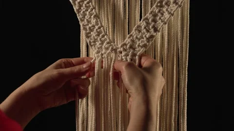 Women's hands weave a macrame pattern in creative workshop on black background Stock Footage 172241342