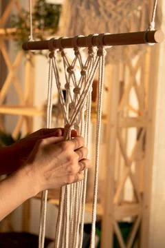 Women's hands weave a macrame pattern in Boho style. A woman ties knots on Stock Photos