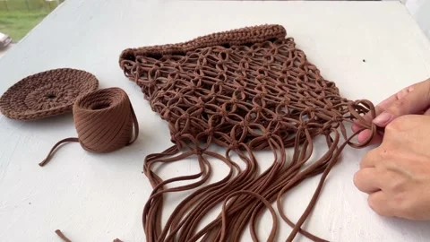 Women's hands weaving a string bag from a knitted cord in the macrame technique. Stock Footage 204855741