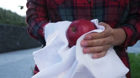 Women's hands wipe apple with a white towel at the market. Hygiene. Stock Footage 139057199