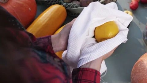 Women's hands wipe lemon with a white towel at the market. Top view. Hygiene. Stock Footage 139058067