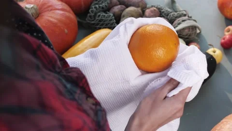 Women's hands wipe orange with a white towel on the market. Top view. Hygiene. Stock Footage 139058009