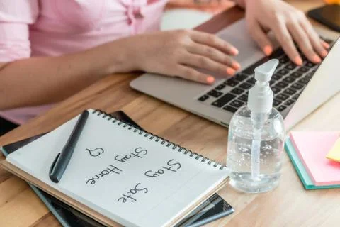 Women's hands working at home, with a computer and a satay safe sign, stay ho Stock Photos