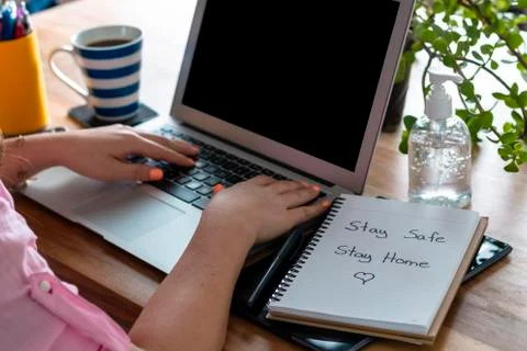 Women's hands working at home, with a computer and a satay safe sign, stay ho Stock Photos