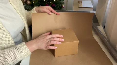 Women's hands wrap a box in wrapping paper, decorating Christmas gifts Stock Footage 258047285