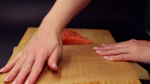Women's hands wrap fresh, raw pieces of salmon in food paper. Stock Footage 221264479