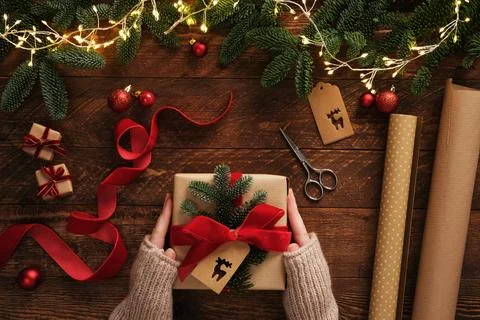 Women's hands wrapping a gift. A table with handmade items, rolls of kraft br Stock Photos