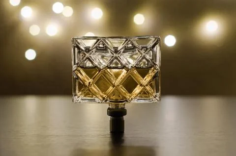 Women's perfume upside down on the background of festive lights. Stock Photos