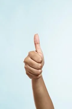 Women's thumbs up hand on plain background Foto stock