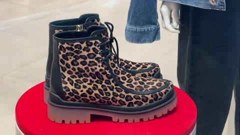 Women's winter fur boots with leopard print stand in the window of a shoe store Stock Footage 221203985