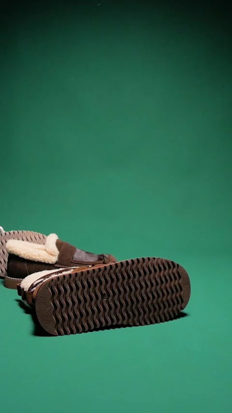 Womens winter shoes falling down against a green background. Fast fashion. Stock Footage 310736960