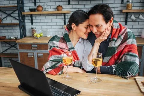 Womn sit with man at table in kitchen. She hold her hand on his cheek and lean Foto stock