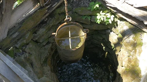 Wonderful old stone well with a bucket full of fresh water rising from it Stock Footage