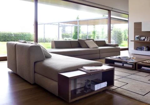 Wood and grey fabric sofas in a modern living room with large windows Stock Photos