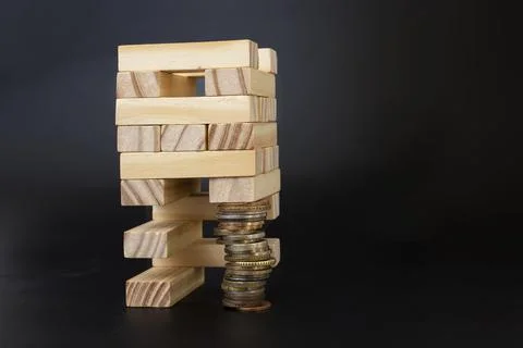 Wood blocks structure supported by a stack of coins. Stock Photos