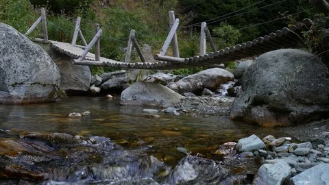 Wood Bridge Over Mountain river flows between the stones Video stock 79749863