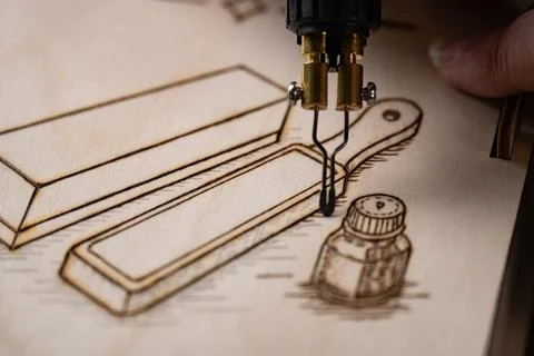 Wood burning tool creating pyrography pattern on wooden board Stock Photos