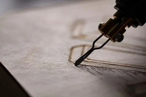 Wood burning tool creating pyrography pattern on wooden board 스톡 사진