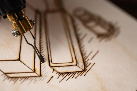 Wood burning tool creating pyrography pattern on wooden board Stock Photos