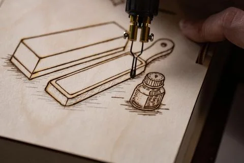 Wood burning tool creating pyrography pattern on wooden board Stock Photos